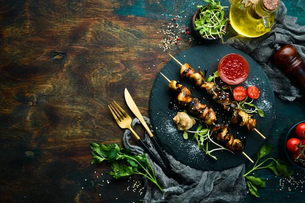 Siyah taştan bir tabakta sebzeli Rapana şişleri. Restoran yemeği. Deniz ürünleri. Kırsal tarzda. Düz Yat.
