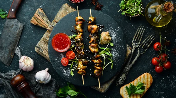 Siyah taştan bir tabakta sebzeli Rapana şişleri. Restoran yemeği. Deniz ürünleri. Kırsal tarzda. Düz Yat.