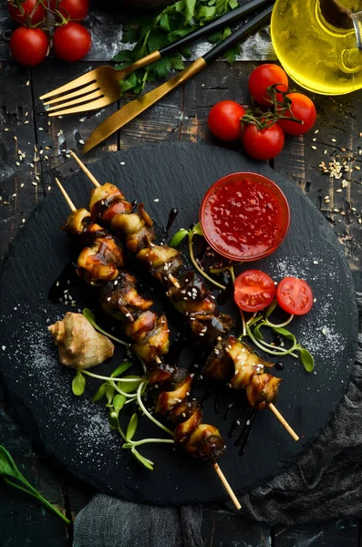 Siyah taştan bir tabakta sebzeli Rapana şişleri. Restoran yemeği. Deniz ürünleri. Kırsal tarzda. Düz Yat.