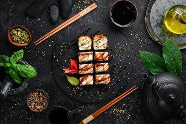 Suşi, siyah bir tabakta yılan balığı, salatalık ve peynirle yuvarlanır. Japon mutfağı. Üst görünüm.