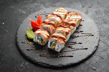 Suşi, siyah bir tabakta yılan balığı, salatalık ve peynirle yuvarlanır. Japon mutfağı. Üst görünüm.