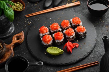 Siyah taş tabakta balık ve havyarla iştah açıcı suşi ruloları. Japon mutfağı. Üst görünüm.