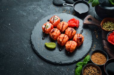 Black Stone tabağında geleneksel suşi rulosu iştah açıcı. Japon mutfağı. Üst görünüm.