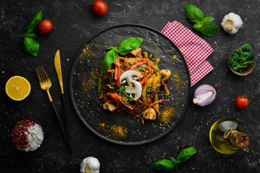 Siyah taş bir tabakta fırında pişmiş tava sebzeleri. Asya mutfağı. Üst görünüm.