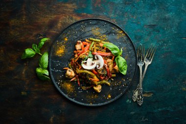 Siyah taş bir tabakta fırında pişmiş tava sebzeleri. Asya mutfağı. Üst görünüm.