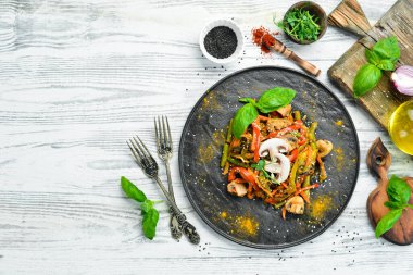 Siyah taş bir tabakta fırında pişmiş tava sebzeleri. Asya mutfağı. Üst görünüm.