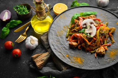 Siyah taş bir tabakta fırında pişmiş tava sebzeleri. Asya mutfağı. Üst görünüm.