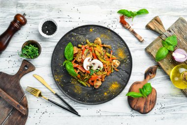 Siyah taş bir tabakta fırında pişmiş tava sebzeleri. Asya mutfağı. Üst görünüm.