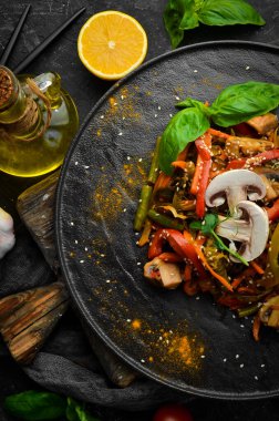 Siyah taş bir tabakta fırında pişmiş tava sebzeleri. Asya mutfağı. Üst görünüm.