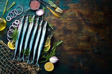 Çiğ taze balık Saira ve siyah taş tabakta baharatlar. Deniz ürünleri. Karanlık bir arka planda.