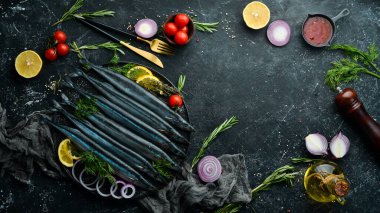 Çiğ taze balık Saira ve siyah taş tabakta baharatlar. Deniz ürünleri. Karanlık bir arka planda.