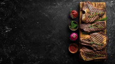 Tahtada ızgara et bifteği: t-bone, striploin, kaburga, New York bifteği. Üst Manzara. Kırsal biçim.