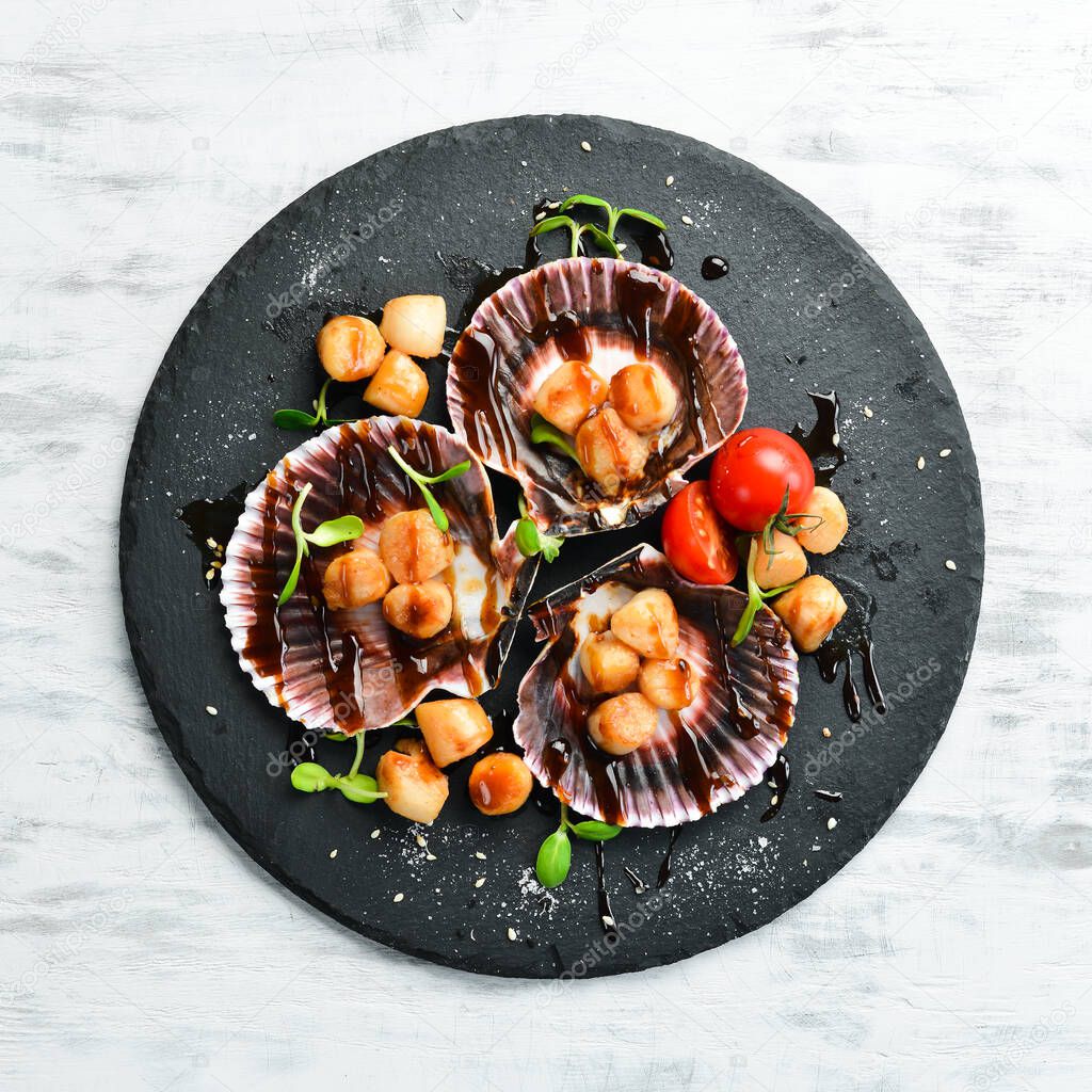 Baked scallops in shells with vegetables on a black stone plate. Luxury restaurant food. Seafood. Rustic style. Flat Lay.