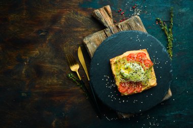 Sandviç. Humus, domates ve yumurtalı taze ciabatta. Kahvaltıda. Siyah taştan bir tabakta.