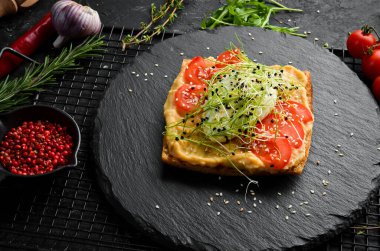 Sandviç. Humus, domates ve yumurtalı taze ciabatta. Kahvaltıda. Siyah taştan bir tabakta.