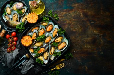 Kızarmış midye, sarımsak, maydanoz, limon ve baharatlı tava. Siyah taştan bir arka planda. Metin için boş alan.