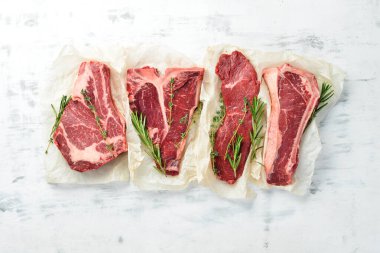 Çiğ biftek seti: biftek, striploin, pirzola, New York bifteği. Üst Manzara. Beyaz ahşap arka planda.