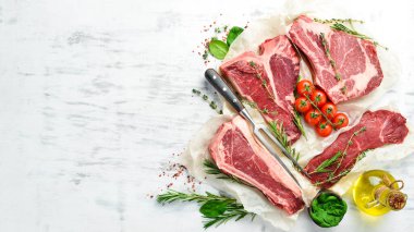 Çiğ biftek seti: biftek, striploin, pirzola, New York bifteği. Üst Manzara. Beyaz ahşap arka planda.