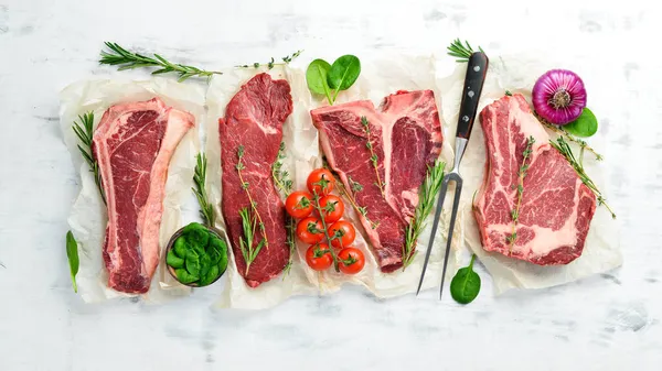 Çiğ biftek seti: biftek, striploin, pirzola, New York bifteği. Üst Manzara. Beyaz ahşap arka planda.