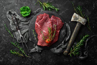 - Et. Biberiye ve baharatlı çiğ dana biftek. Siyah taştan bir arka planda. Üst görünüm.