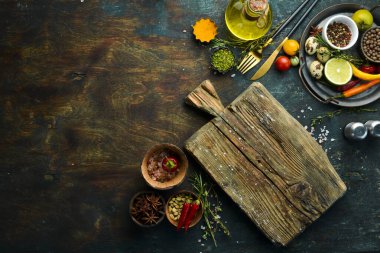 Sebzeler ve baharatlarla dolu siyah taş bir masanın üzerinde tahta tahta bir tahta. Yemek arkaplanı. Üst Manzara. Kırsal biçim.