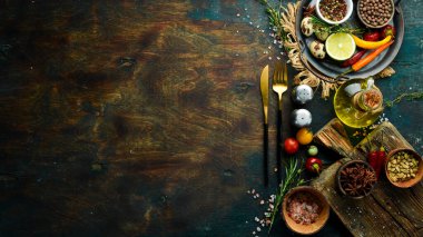 Sebze ve baharatlı siyah taş bir masanın üzerindeki çatal bıçak takımı. Yemek arkaplanı. Üst Manzara. Kırsal biçim.