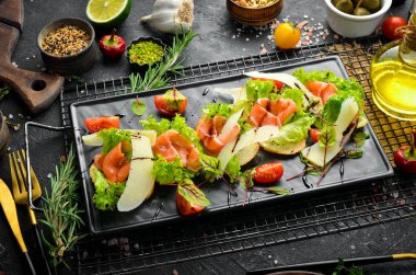 Siyah tabakta somon, marul ve parmesan peyniri. Üst Manzara. Kırsal biçim.