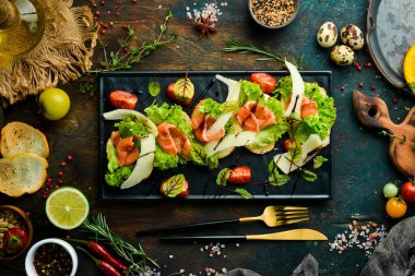 Siyah tabakta somon, marul ve parmesan peyniri. Üst Manzara. Kırsal biçim.