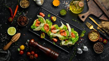 Siyah tabakta somon, marul ve parmesan peyniri. Üst Manzara. Kırsal biçim.