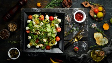 Mozzarella peynirli sebze salatası. Siyah bir tabakta. Üst Manzara. Yiyecekler. Kırsal biçim.
