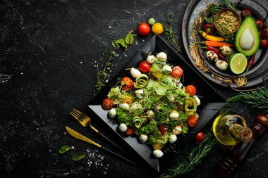 Mozzarella peynirli sebze salatası. Siyah bir tabakta. Üst Manzara. Yiyecekler. Kırsal biçim.