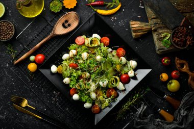 Mozzarella peynirli sebze salatası. Siyah bir tabakta. Üst Manzara. Yiyecekler. Kırsal biçim.