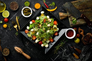 Mozzarella peynirli sebze salatası. Siyah bir tabakta. Üst Manzara. Yiyecekler. Kırsal biçim.