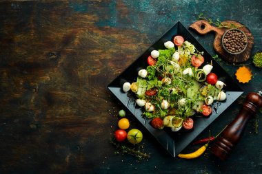Mozzarella peynirli sebze salatası. Siyah bir tabakta. Üst Manzara. Yiyecekler. Kırsal biçim.