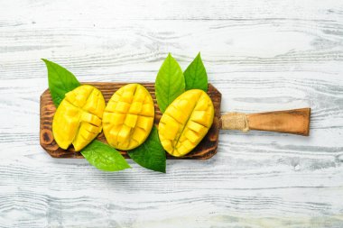 Beyaz ahşap bir arka planda tatlı mango dilimleri. Kırsal tarzda. Üst Manzara. Tropik meyveler.