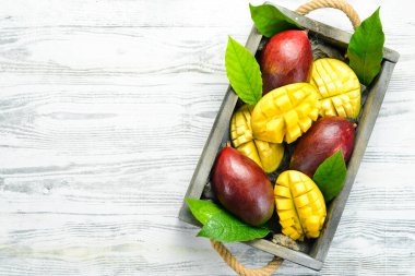 Beyaz ahşap bir arka planda tatlı mango dilimleri. Kırsal tarzda. Üst Manzara. Tropik meyveler.