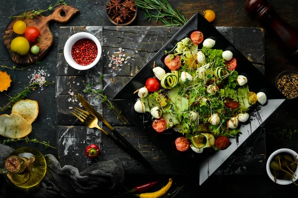 Mozzarella peynirli sebze salatası. Siyah bir tabakta. Üst Manzara. Yiyecekler. Kırsal biçim.