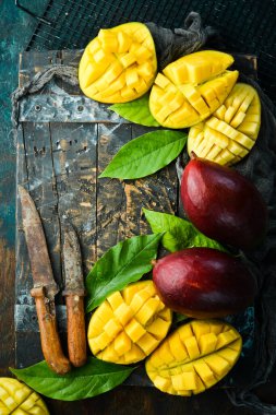 Eski ahşap arka planda yaprakları olan taze, tatlı mango. Kırsal tarzda. Üst Manzara. Tropik meyveler.