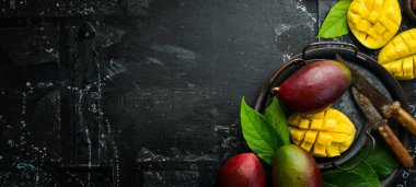 Eski ahşap arka planda yaprakları olan taze, tatlı mango. Kırsal tarzda. Üst Manzara. Tropik meyveler.