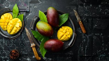 Eski ahşap arka planda yaprakları olan taze, tatlı mango. Kırsal tarzda. Üst Manzara. Tropik meyveler.