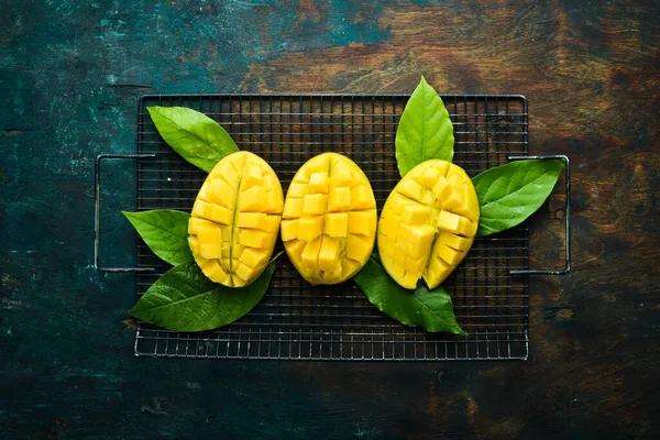 Eski ahşap arka planda yaprakları olan taze, tatlı mango. Kırsal tarzda. Üst Manzara. Tropik meyveler.