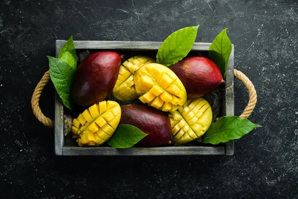 Mango ahşap bir kutuya konmuş. Tropik meyveler. Kopyalama alanı olan üst görünüm.