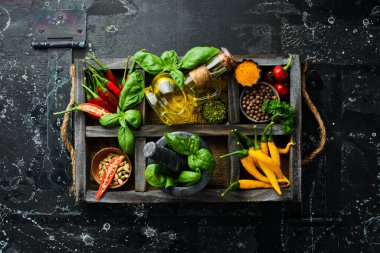 Tahta bir kutuda baharatlar: fesleğen, biber, yağ, kırmızı biber, bitkiler. Yemek arkaplanı. Üst görünüm.