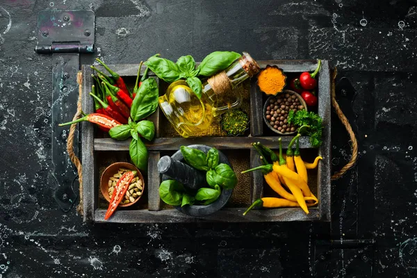 Tahta bir kutuda baharatlar: fesleğen, biber, yağ, kırmızı biber, bitkiler. Yemek arkaplanı. Üst görünüm.