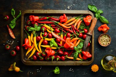 Siyah taştan bir arka planda koyu kırmızı biberlerin arka planı. Meksika mutfağı. Baharatlar. Üst görünüm.