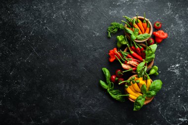 Siyah taştan bir arka planda koyu kırmızı biberlerin arka planı. Meksika mutfağı. Baharatlar. Üst görünüm.