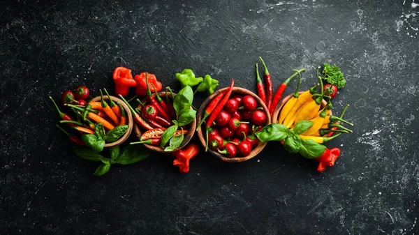 Siyah taştan bir arka planda koyu kırmızı biberlerin arka planı. Meksika mutfağı. Baharatlar. Üst görünüm.