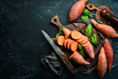 Siyah bir arka planda çiğ patates ve fesleğen. Üst Manzara. Metnin için boş yer.