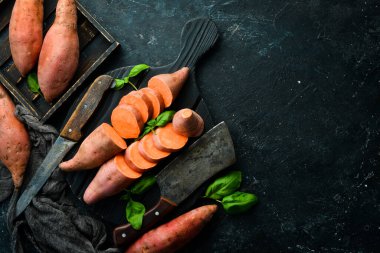 Siyah bir arka planda çiğ patates ve fesleğen. Üst Manzara. Metnin için boş yer.