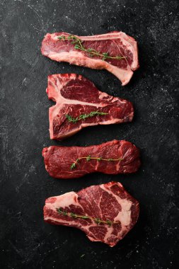 Çiğ siyah Angus Prime bifteği: T-bone, striploin, Rib, New York bifteği. Üst Manzara. Taş bir arka planda.